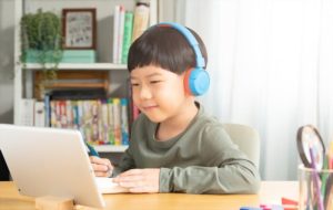 small boy uses laptop to make video call with his teacher. screen shows an online lecture with teacher explaining subject from class.